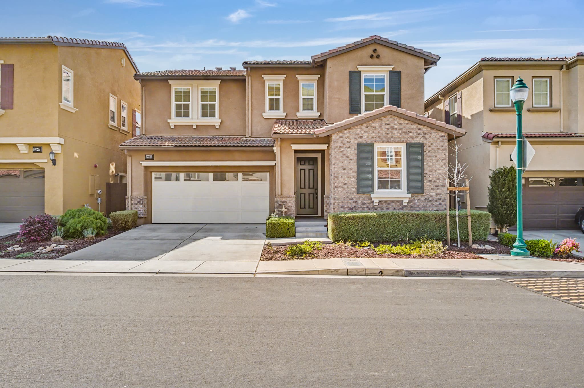 Two-story suburban home exterior with a tile roof, brick accents, and landscaped front yard