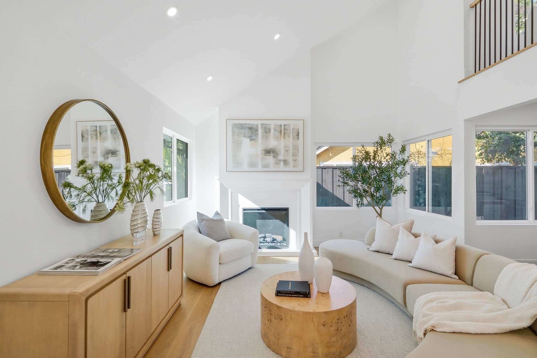 Bright, well-staged living room with a vaulted ceiling and curved sofa