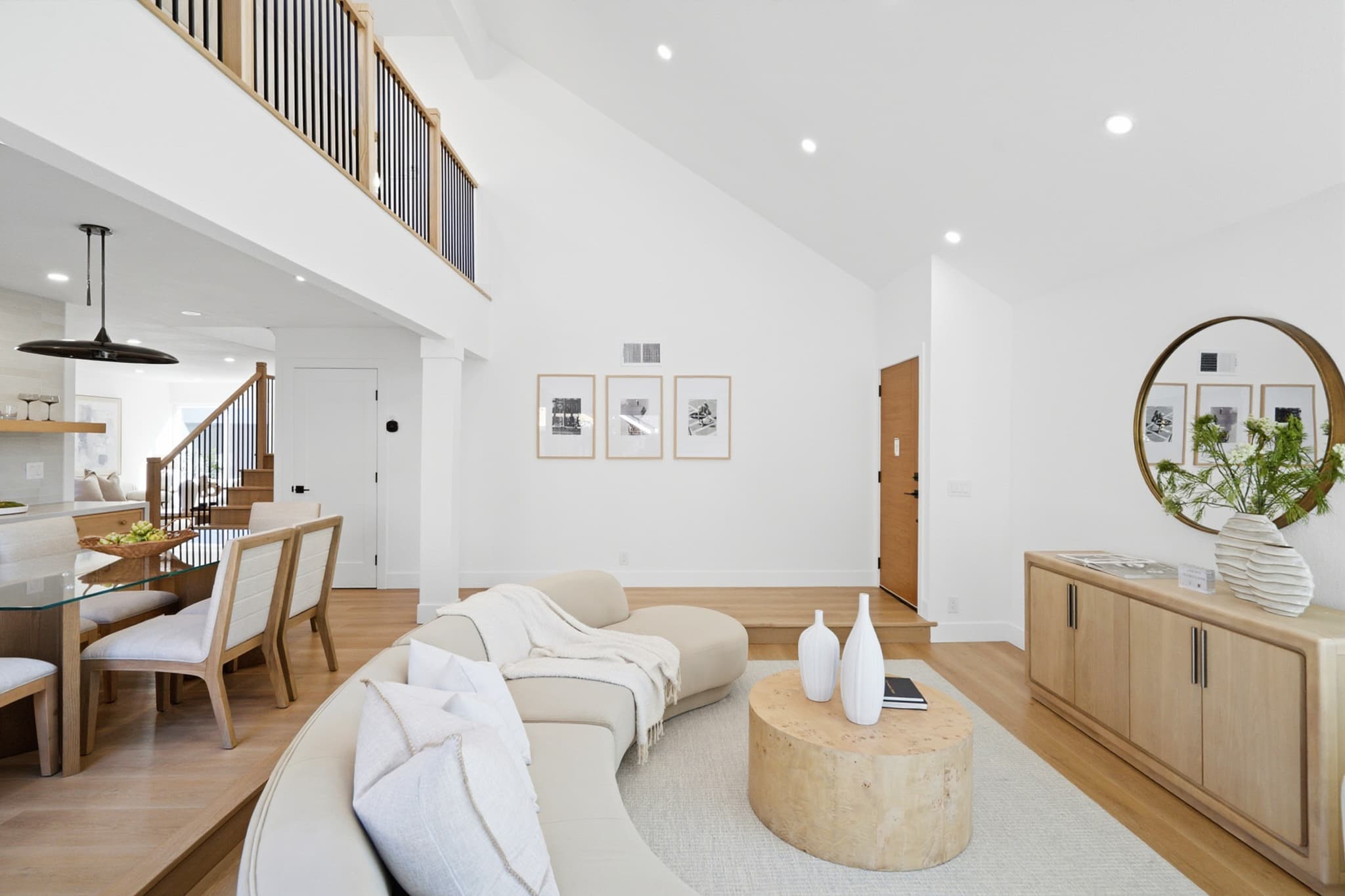 Bright, open-concept living room with a vaulted ceiling and a staircase to a loft