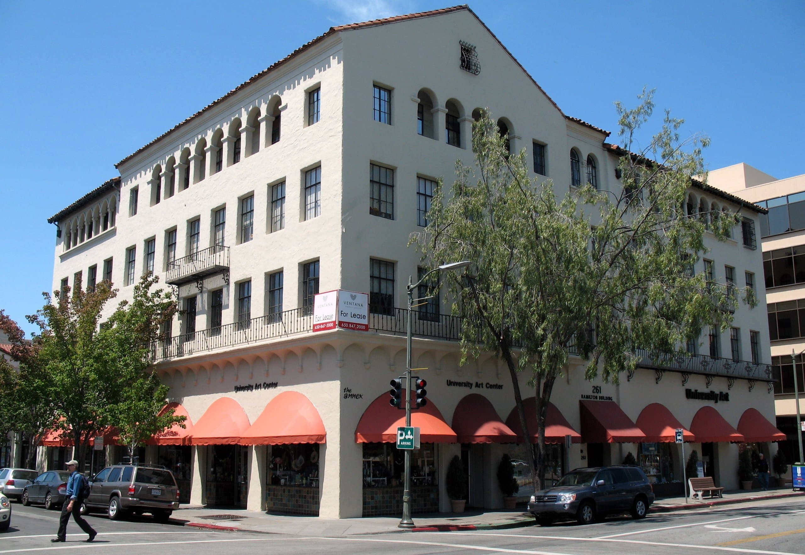 A Spanish Colonial building with red awnings in Palo Alto's Ramona Street Architectural District